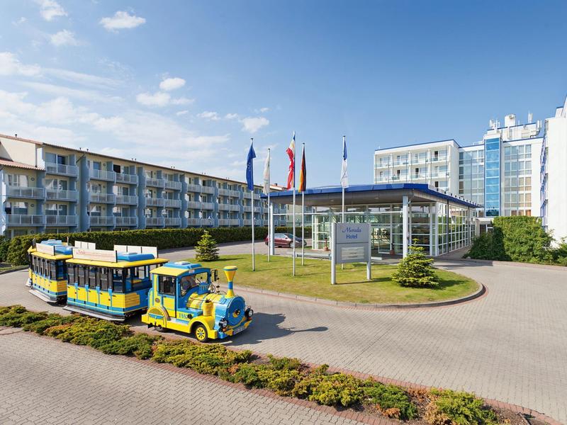 Hotelgebäude mit kleinem bunter Touristenzug und Flaggen bei klarem Himmel