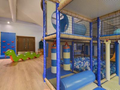 Innen-Spielbereich im Hotel mit Klettergerüst, Bällebad und Wippe in Form eines Drachens.