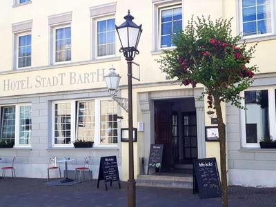 Exterior view of Hotel Stadt Barbing with seating and signs outside the entrance.