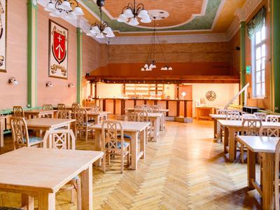 Brightly furnished dining room with wooden tables and chairs, decorated with wall crests.