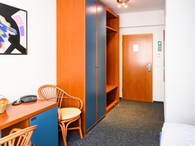 Hotelzimmer mit Holzmöbeln, Stühlen und einem Schreibtisch, heller und sauberer Raum.