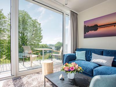 Cozy living room with blue sofa, large window, and view of terrace and garden.