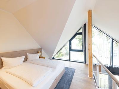 Bright attic bedroom with large bed and window overlooking greenery.