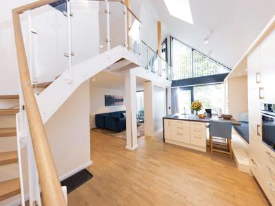 Bright modern living room with wooden staircase and open kitchen in a loft apartment.