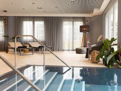 Modern indoor pool with steps, comfortable seating, and large windows for natural light.