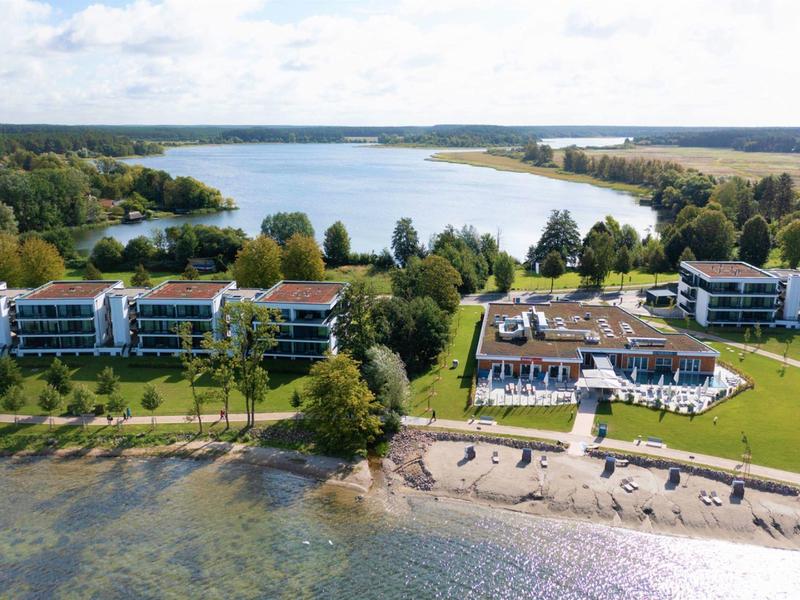 Holiday resort with residential buildings and beach by a lakeshore with views of water and forest