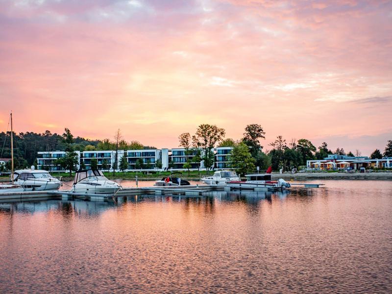 Marina with boats and hotels at sunset over calm water.