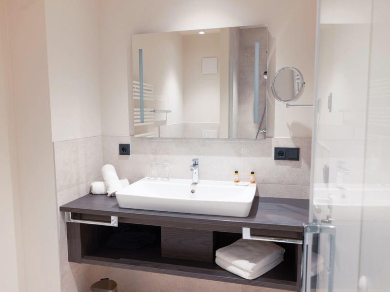 Modern bathroom with white sink, large mirror, and towels
