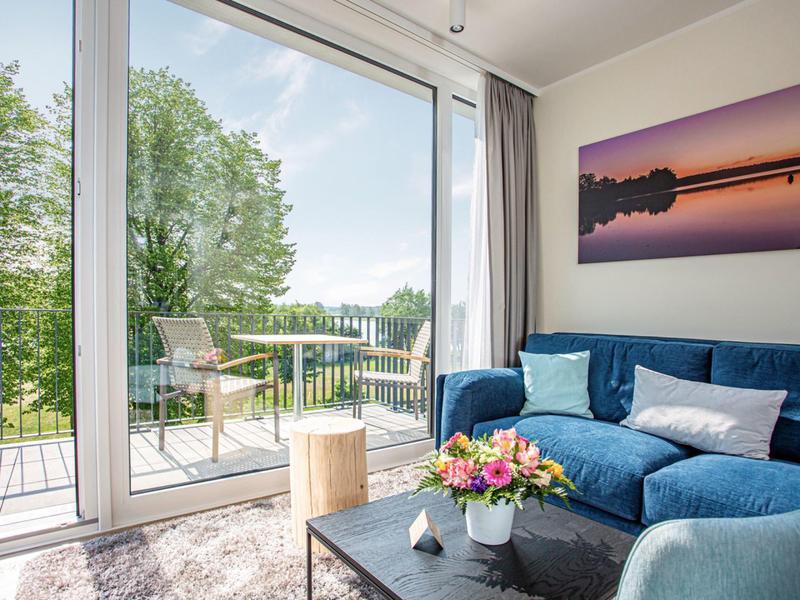 Cozy living room with blue sofa, large window, and view of terrace and garden.