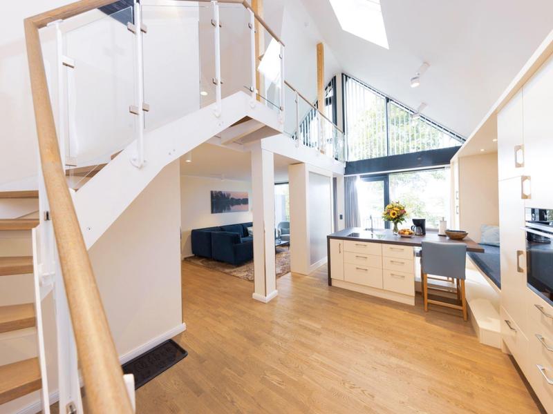 Bright modern living room with wooden staircase and open kitchen in a loft apartment.