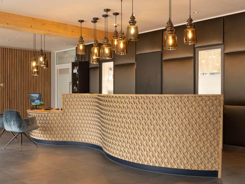 Modern hotel reception with wavy front desk and warm hanging lights.