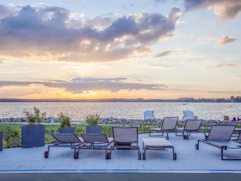 Several lounge chairs on terrace overlooking the sea at sunset