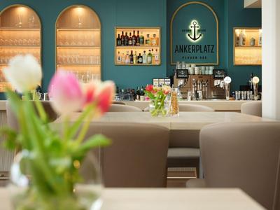 Innenansicht einer modernen Hotelbar mit bequemen Sesseln und frischen Blumen auf einem Tisch.