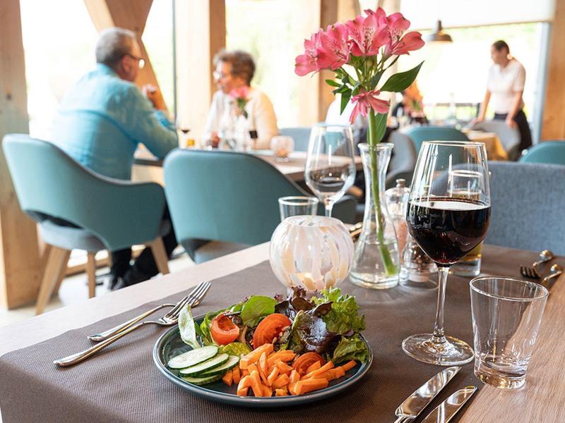 Mesa elegante con ensalada y bebidas en un restaurante luminoso.