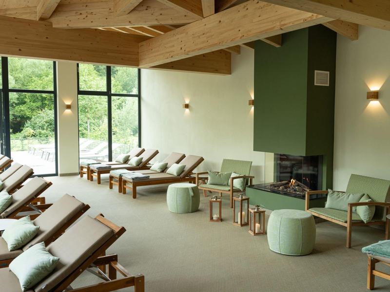 Área de salón acogedora con paredes verdes, vigas de madera y tumbonas en un hotel.