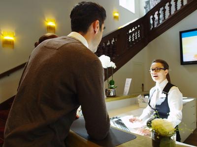 A guest talks to a hotel receptionist sitting behind the counter.