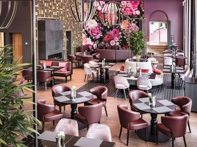 Modern restaurant with pink and beige furniture, floral wall decoration, and large windows.