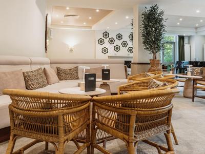 Heller Hotel-Loungebereich mit Rattanstühlen, Sofas und moderner Dekoration.