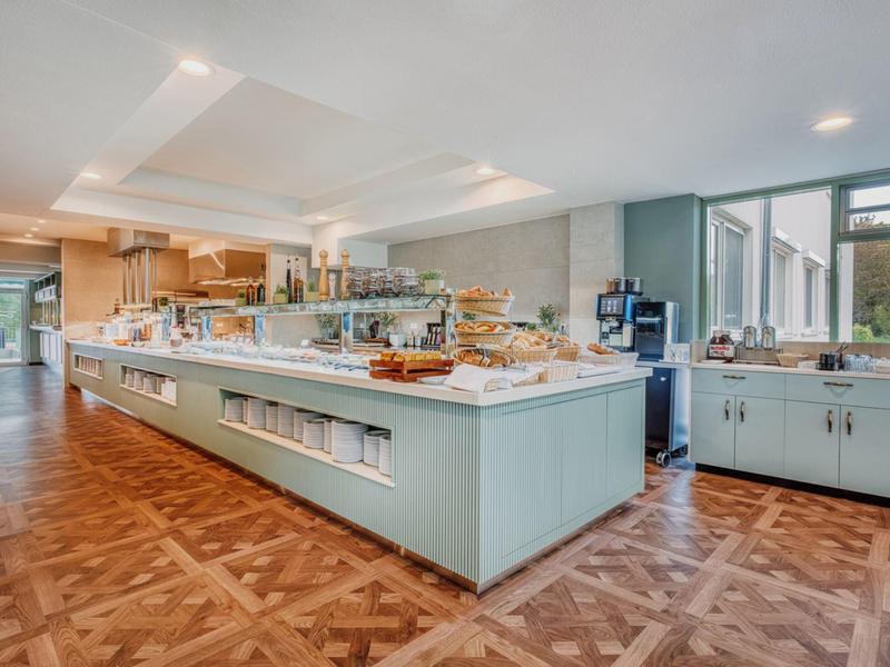 Hell beleuchtetes Buffet in einem modernen Hotel mit Holzboden und großen Fenstern.