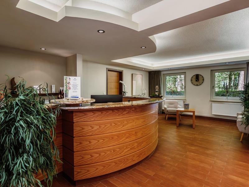 Ein moderner Empfangsbereich mit hellem Holzelement und Pflanzen.