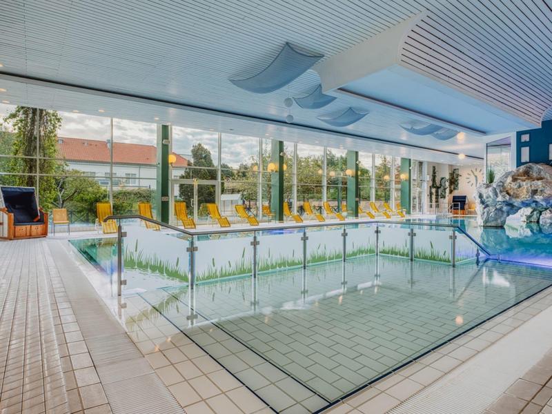 Moderner Innenpool mit großen Fensterfronten und Liegestühlen in einem Hotel.