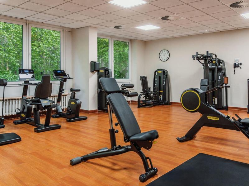 Helles Fitnessstudio mit modernen Trainingsgeräten und großen Fenstern.