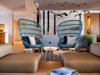 Gemütlicher Hotel-Loungebereich mit modernen Stühlen, Tischen und einladender Dekoration.