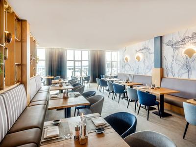 Světla restaurace s pohodlnými lavicemi, modrými židlemi a elegantními dekoracemi stolů.