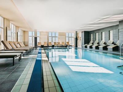 Indoor pool with comfortable lounge chairs and large windows letting in natural light.