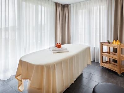 Treatment room with massage table covered in beige cloth and soft light through sheer curtains.