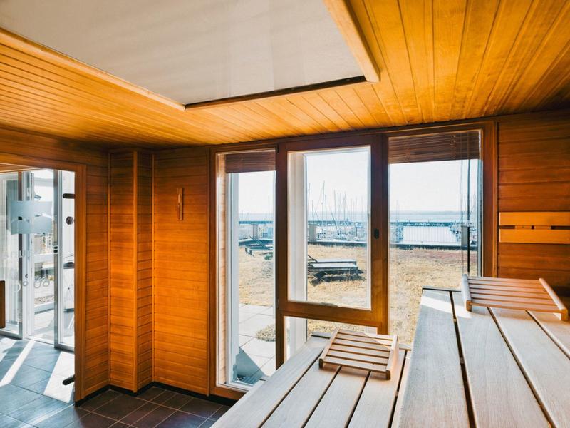 Sauna with wooden benches and glass sliding door with outside view.