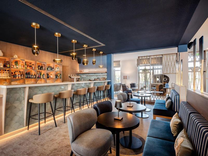 Elegant hotel bar with modern chairs, wood and marble details, atmospheric lighting.
