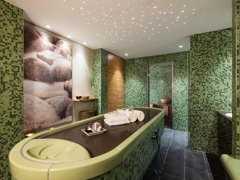 Modern treatment room with green massage table and calming wall decoration.
