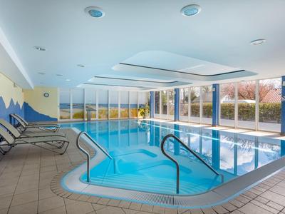 Piscine intérieure d'hôtel avec grandes fenêtres et chaises longues