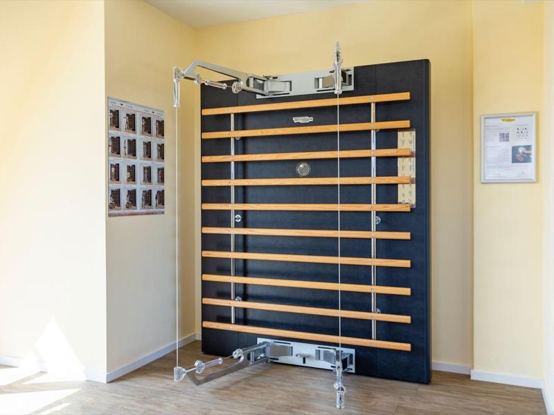 Mur d'entraînement moderne avec poignées dans une chambre beige clair avec parquet.