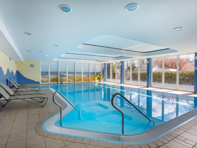 Piscine intérieure d'hôtel avec grandes fenêtres et chaises longues