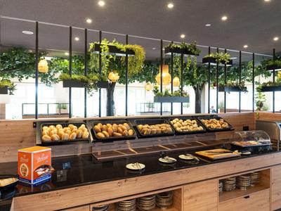 Buffet moderne avec des pâtisseries fraîches et des plantes vertes au-dessus d'un comptoir en bois dans un restaurant.
