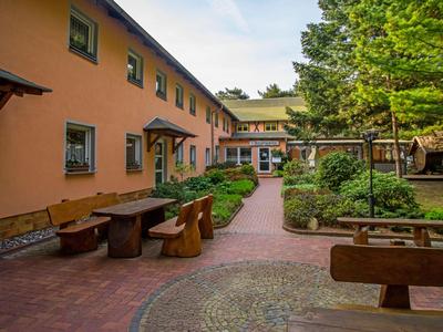 Dziedziniec hotelowy z miejscami do siedzenia i zielonymi roślinami pod niebieskim niebem.