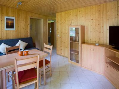 Przytulny salon z drewnianymi meblami, stołem jadalnym i telewizorem w pokoju hotelowym.