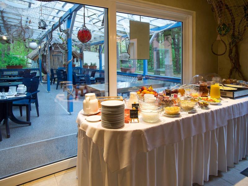 Tavolo buffet per la colazione vicino a porte di vetro con vista sulla terrazza all'aperto.