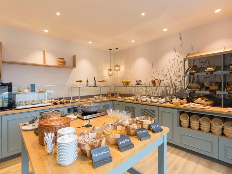 Helles Buffet mit verschiedenen Brotsorten und Körben in modern eingerichteter Frühstücksecke.