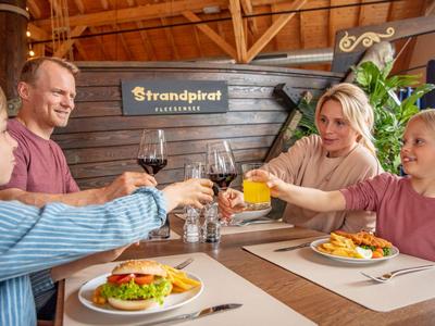 Quattro persone brindano con bevande in un ristorante, con hamburger sul tavolo.