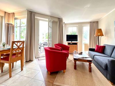 Salon lumineux avec coin salon, table à manger et accès au balcon avec vue sur la verdure.