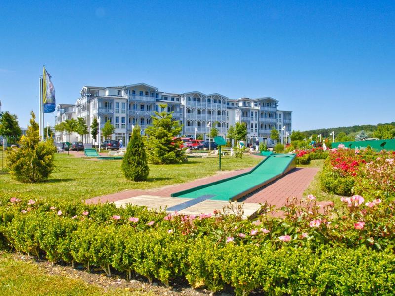 Luxusní hotel s rozlehlou zahradou a minigolfem pod modrou oblohou