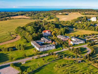 Widok z lotu ptaka hotelu i okolicy z polami i lasami pod niebieskim niebem.