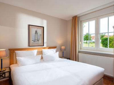 Camera luminosa con letto matrimoniale, comodini e finestra con vista sul verde.