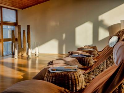 Area relax accogliente con sedie in vimini, cuscini e luce naturale nell'area benessere.