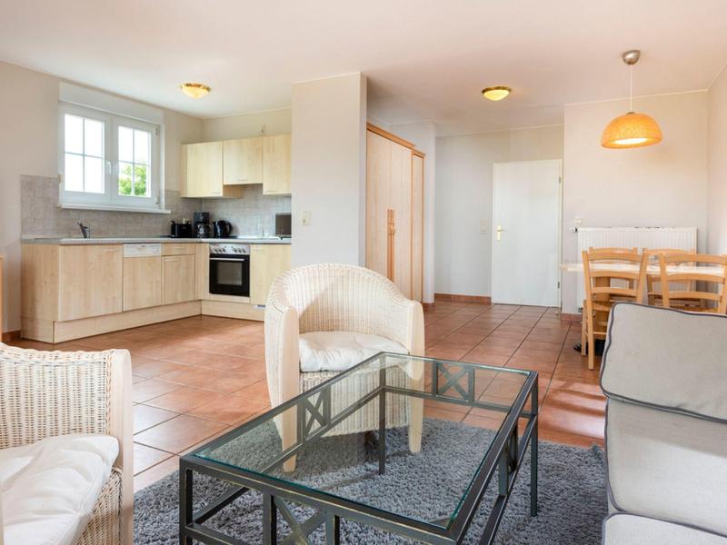 Soggiorno luminoso con mobili bianchi, tavolino in vetro e zona pranzo in cucina aperta.