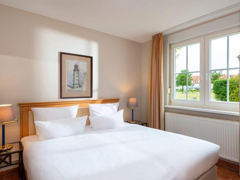 Camera luminosa con letto matrimoniale, comodini e finestra con vista sul verde.