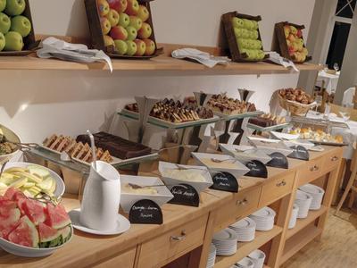 Buffet with fresh fruit, pastries, and various breakfast options in a bright dining area.